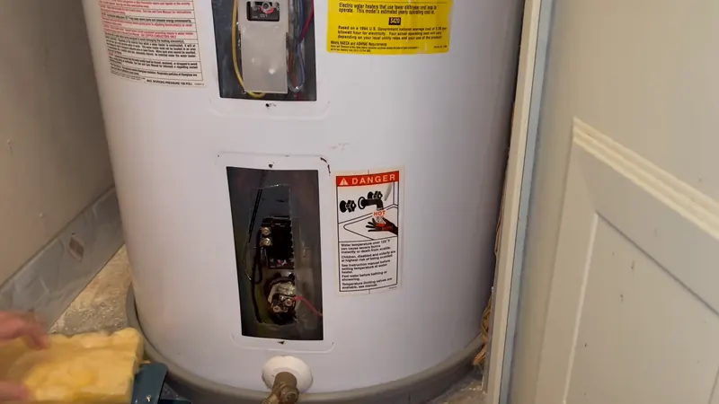 Electric water heater with access panels open showing the thermostat and heating element before water heater repair in Chester, PA